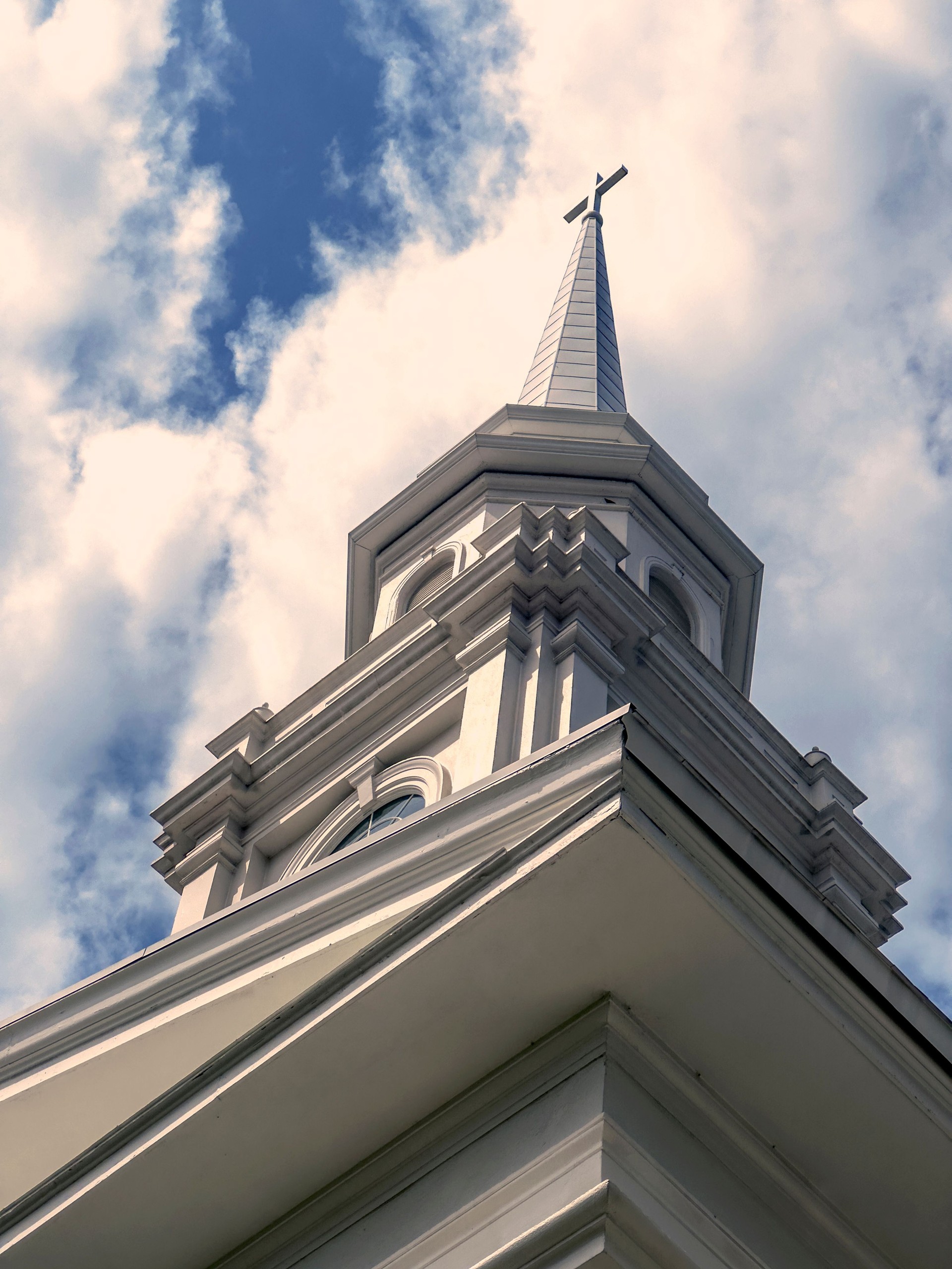 Church exterior with bell tower and cross sign over sky